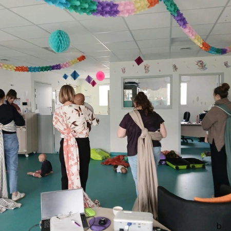Formation au portage physiologique en structure petite enfance : des professionnelles portent des bébés en écharpe dans une salle décorée, favorisant le lien professionnelle/bébé accueilli