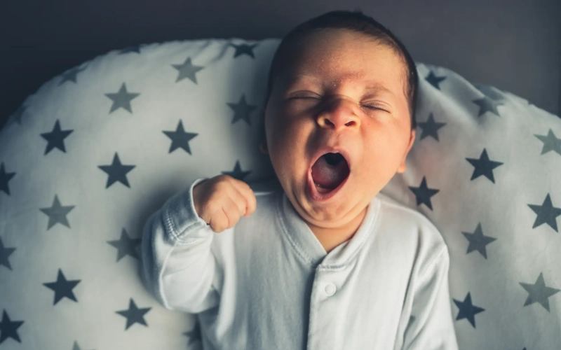 Photo d'un nourrisson en train de bailler dans son lit