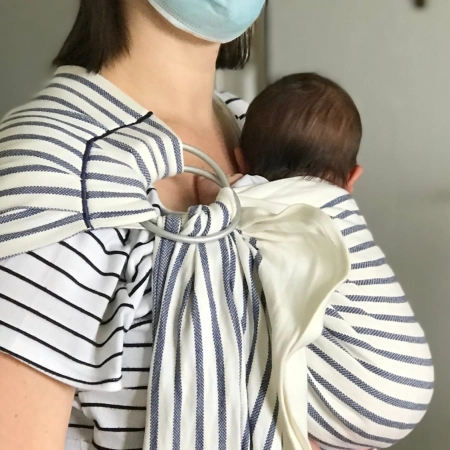 Prpfessionnelle de santé portant un nouveau-né en écharpe sling à la maternité, portage physiologique favorisant le contact et le bien-être du bébé